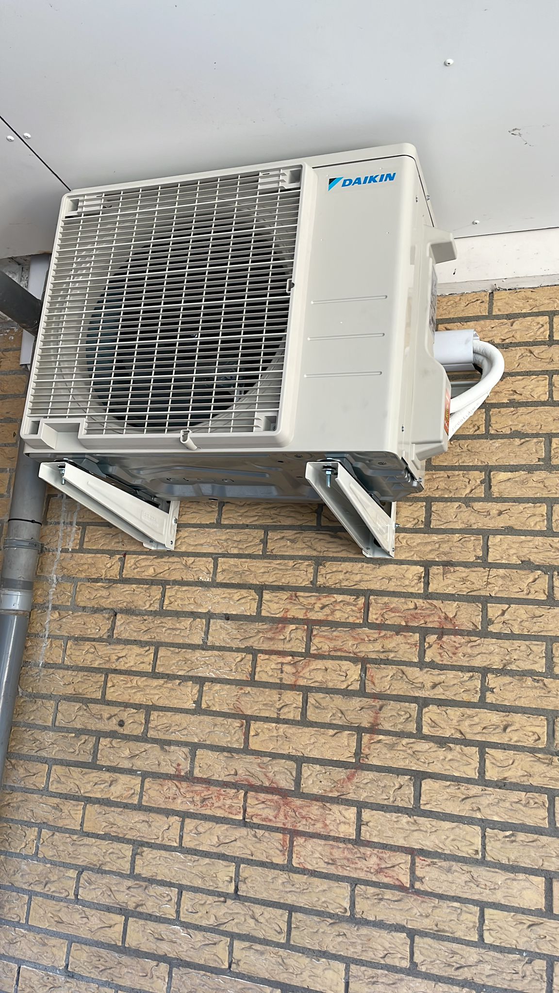 Daikin-buitendeel op beugels aan een gele bakstenen gevel, geplaatst bij Ruud Blanken