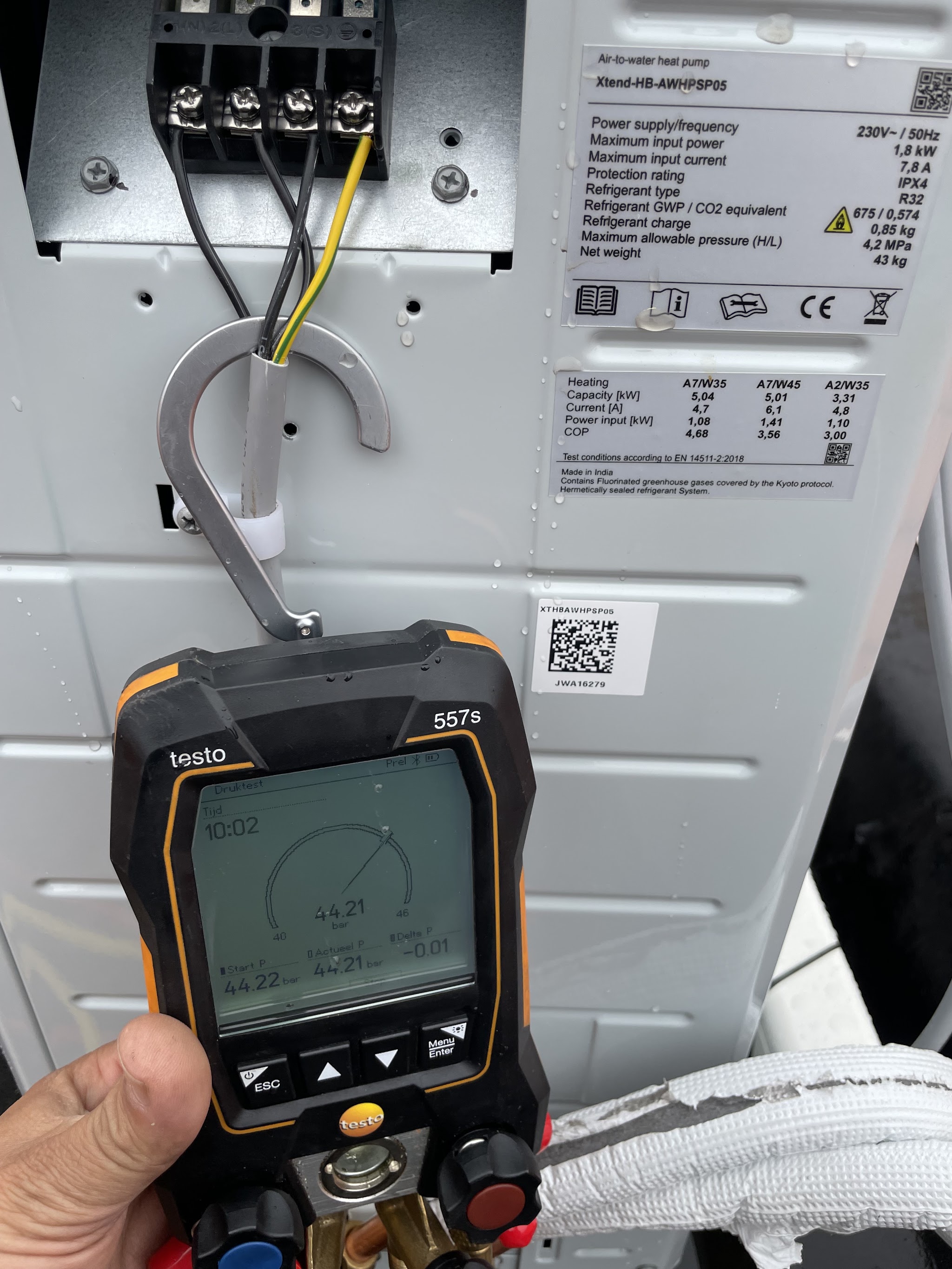 Hand met een Testo digitale meetset voor het typeplaatje van een lucht-water-warmtepomp